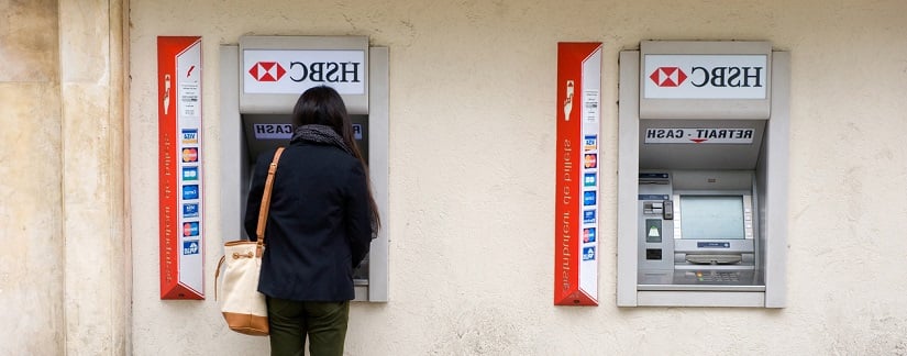 Une femme retire de l’argent d’un guichet automatique HSBC dans une rue de Paris, en France.