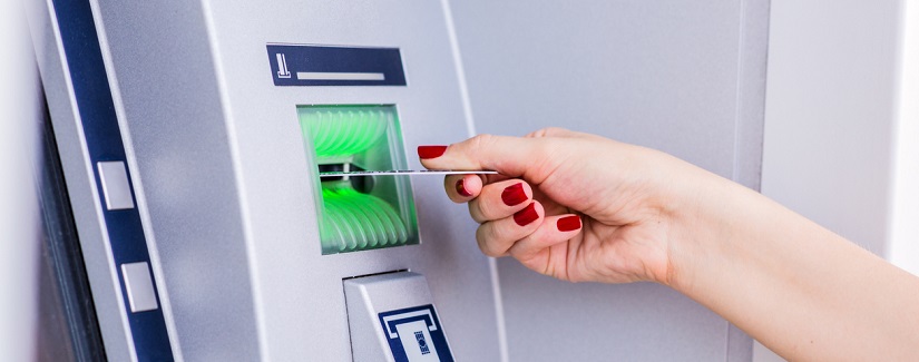 Femme insérant une carte de crédit au guichet automatique.