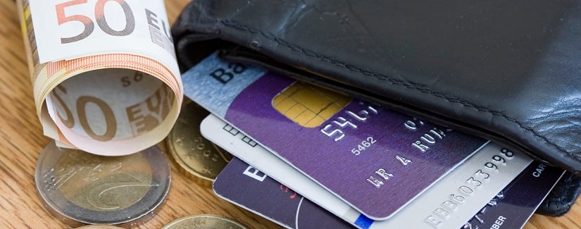 Un portefeuille noir avec un ensemble de cartes de crédit/débit de la Bank of Ireland et quelques pièces de monnaie et des billets de 50 euros à côté