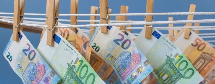 Euro billets de banque accrochés à la corde à linge sèche épingle avec pinces à linge sur fond bleu.