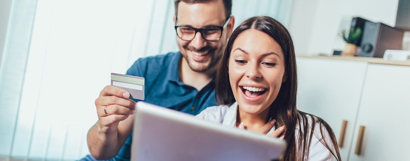 Couple heureux souriant avec ordinateur tablette pc et carte de crédit ou bancaire, achats en ligne à la maison.