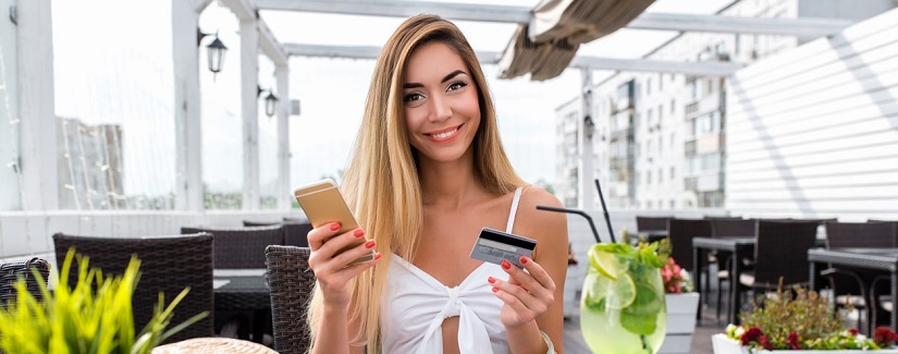 Une jolie jeune fille et heureuse au café d'été, souriant, concept d'achat payant le dîner par carte de crédit.
