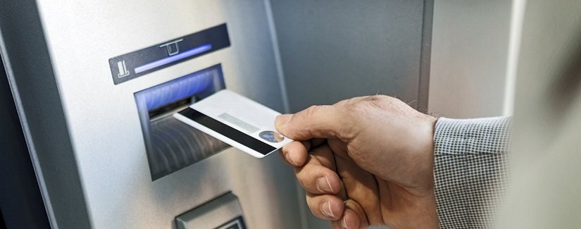 Main d’une personne insérant une carte de crédit sur le guichet automatique.