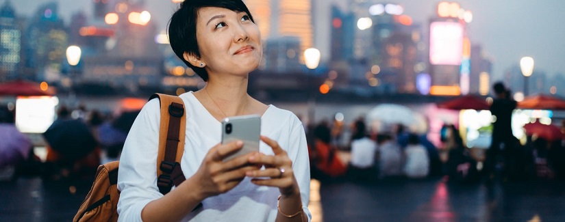 Une jolie femme asiatique tenant son smartphone pour faire de service bancaire en ligne.