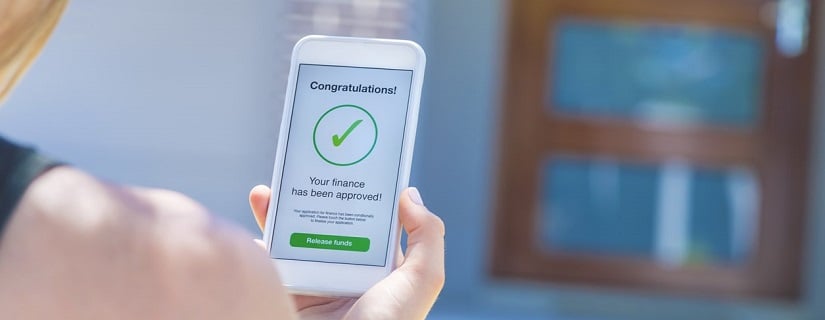 Approbation de prêt hypothécaire sur téléphone mobile devant la maison. 