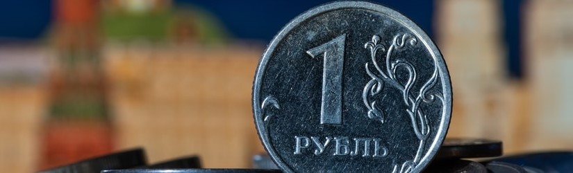 Pièce en coupures de 1 rouble russe sur une pile d’autres pièces devant des fragments symboliques hors de portée du Kremlin de Moscou