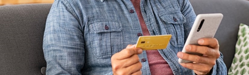 Indien souriant utilisant un téléphone intelligent pour vérifier les transactions par carte de crédit depuis une application.
