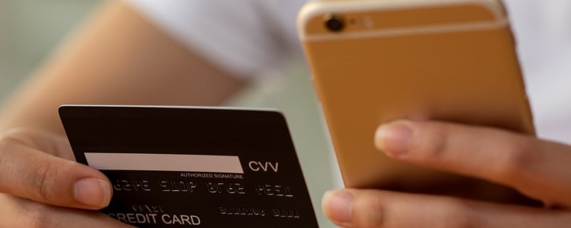 Gros plan d'une main de femme utilisant une carte de crédit et une tablette pour faire des achats en ligne à la maison, concept de paiement, d'achat et d'achat en ligne.