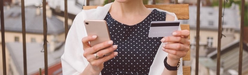 Jeune femme sur le toit d'un restaurant utilisant un téléphone intelligent pour faire des achats en ligne.