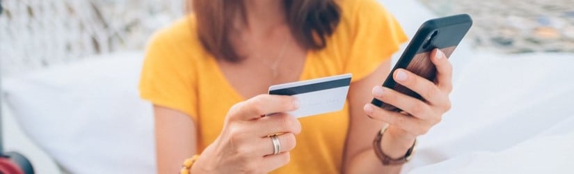 Une femme effectue des paiements par carte de crédit depuis son smartphone.