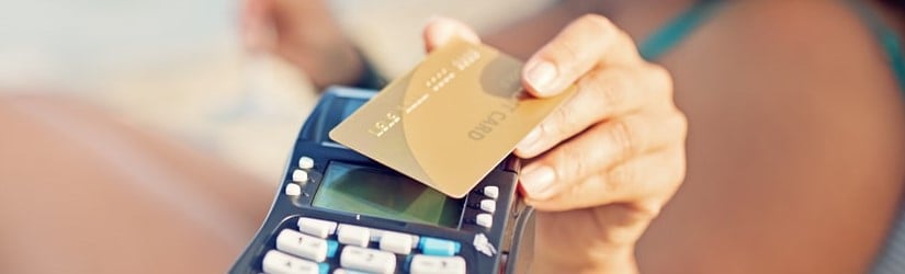 Une femme paie son cocktail sur la plage en utilisant une carte de crédit sans contact.