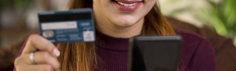 Femme utilisant un téléphone portable et une carte de crédit pour des achats en ligne