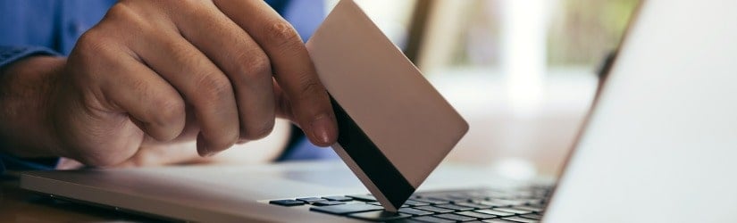 Homme utilisant une carte de crédit pour faire des achats en ligne dans un café.