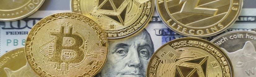 Gros plan sur le bitcoin et les autres crypto-monnaies au-dessus d'un billet de cent dollars. 