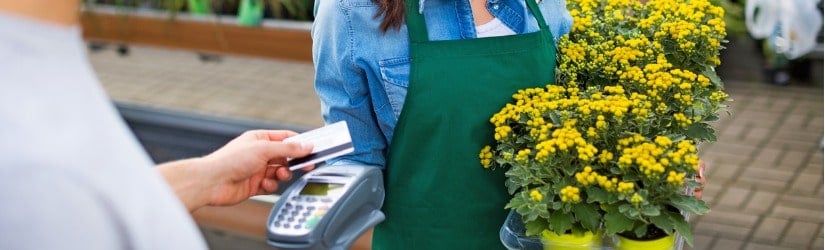 Une jeune fleuriste recevant un paiement avec une carte de crédit d’un client.
