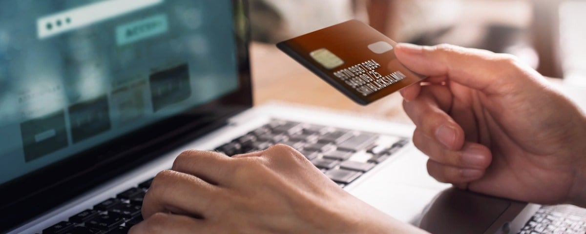 Client utilisant une carte de crédit et un ordinateur portable pour faire des achats en ligne.