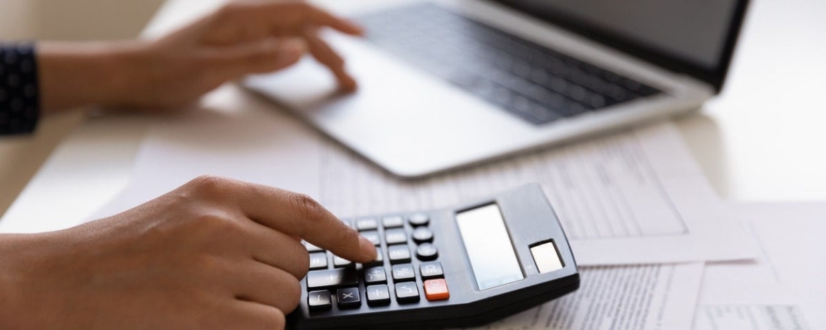 Jeune client féminin de banque électronique utilisant la calculatrice pour calculer ses factures