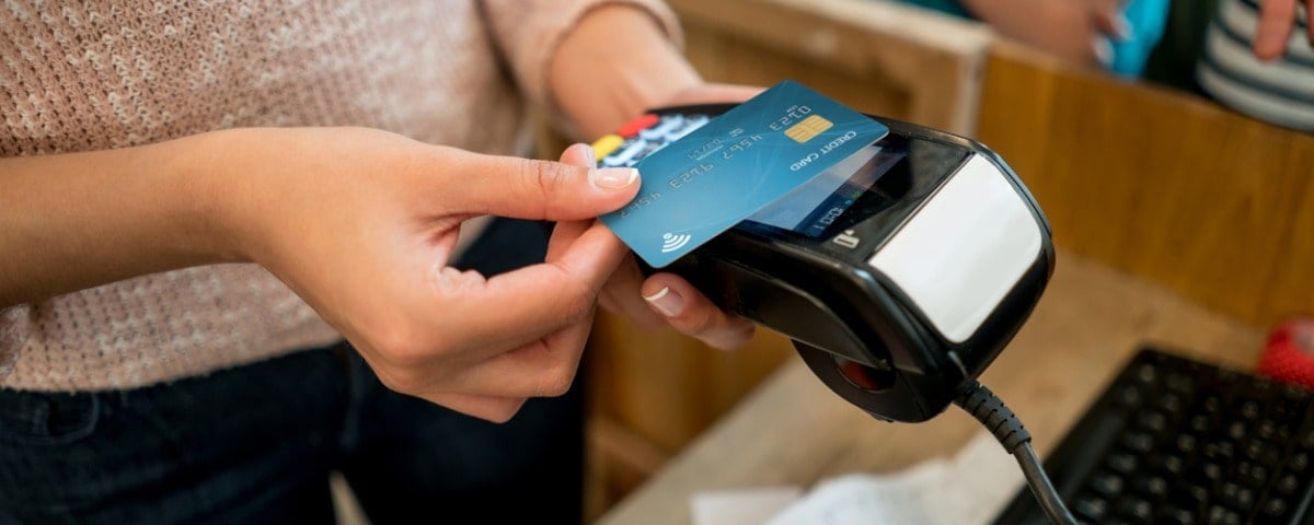 Personne méconnaissable effectuant un paiement sans contact dans un magasin avec une carte de crédit. Le design de la carte de crédit est un design propre.