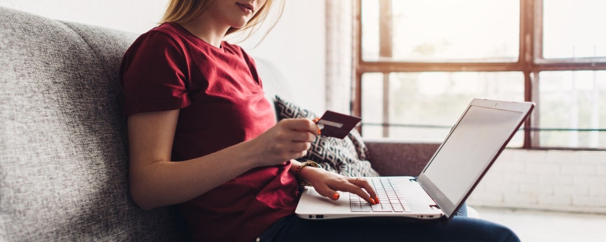 Femme tenant une carte de crédit et un ordinateur portable pour faire des achats en ligne