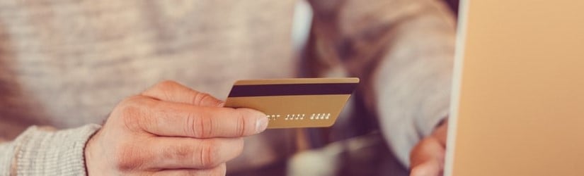 Main d’un homme tenant sa carte de crédit pour faire visiter son compte bancaire en ligne. 