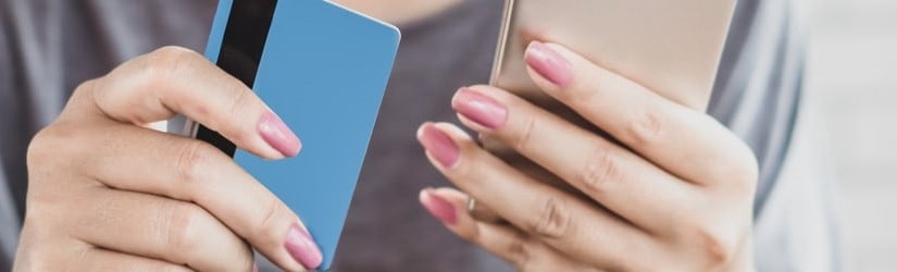 femme calculant à la main ses dépenses et ses dettes de cartes de crédit avec un téléphone intelligent