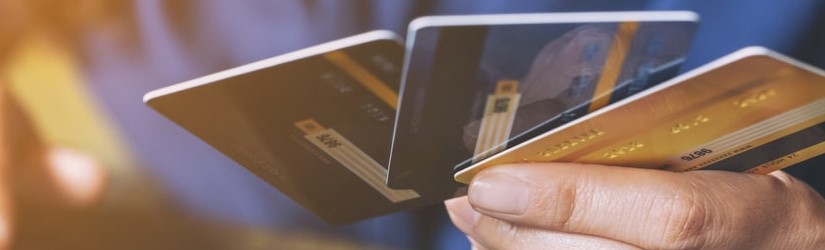 Image rapprochée d'une femme d'affaires tenant des cartes de crédit tout en utilisant un ordinateur portable.