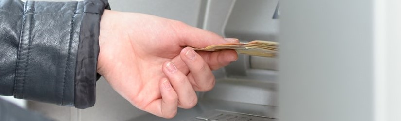 Un homme vient de tirer son argent sur le distributeur automatique de billets.