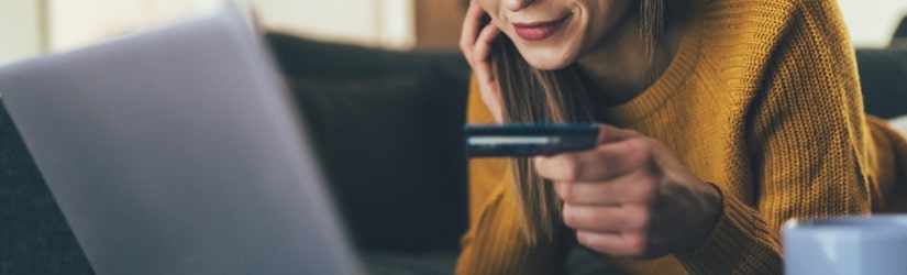 Jeune femme payant en ligne avec une carte de crédit et un ordinateur portable à la maison.