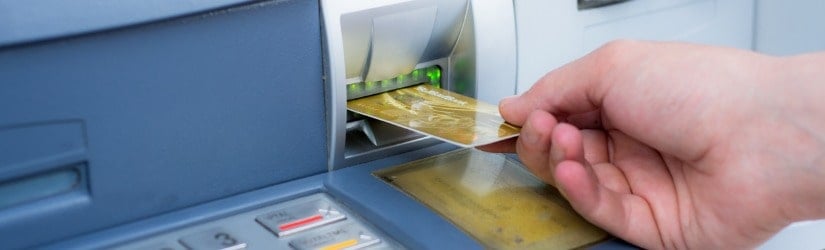Insertion manuelle d'une carte de crédit dans un distributeur automatique de billets.
