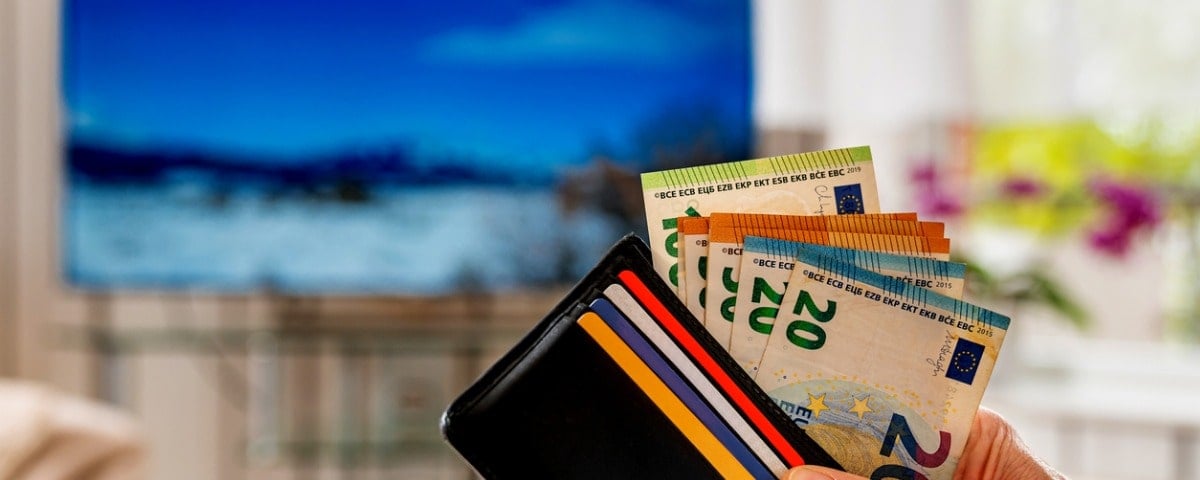 Main d'un homme tenant un portefeuille contenant des billets de banque européens et des cartes en plastique.