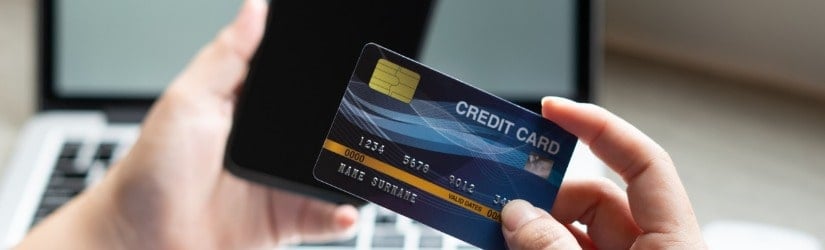 Femme d'affaires tenant à la main une carte de crédit pour faire des achats en ligne sur un ordinateur