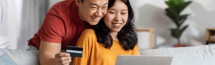 Une famille japonaise souriante paie des biens et des services en ligne tout en restant à la maison.