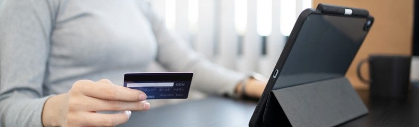 Gros plan d'une main utilisant un téléphone portable et une carte de crédit pour un paiement en ligne, portefeuille électronique