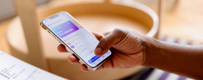 Photo en gros plan d'un jeune homme tenant un téléphone portable et regardant d'un air perplexe une carte de crédit.
