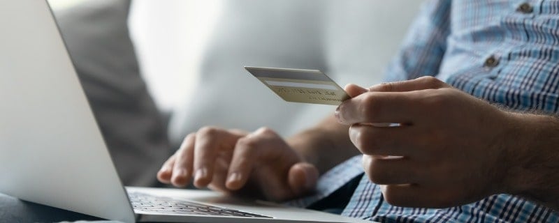 une personne devant son pc, carte de crédit en main