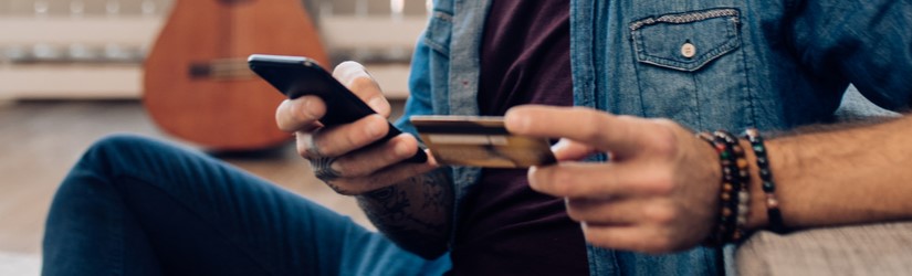 Jeune homme se détendant à la maison et faisant des achats en ligne à l'aide d'un smartphone.