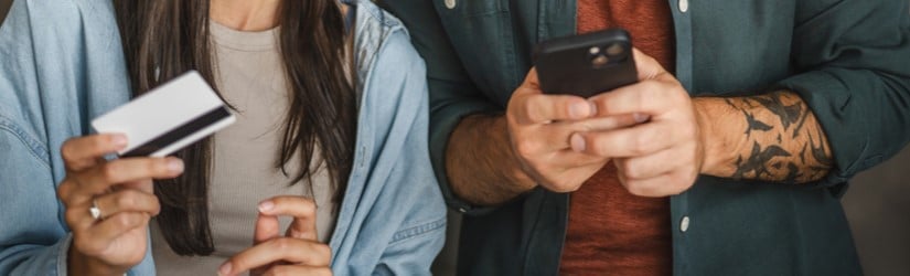 Un couple d'adultes caucasiens achète en ligne sur un téléphone portable avec une carte de crédit à la maison.