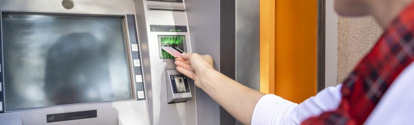 Femme utilisant un distributeur automatique de billets et une carte de crédit pour retirer de l'argent