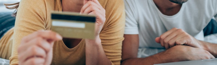 Couple faisant  une réservation d’hôtels en ligne avec une carte de crédit et un ordinateur portable.